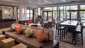 A modern hotel lobby with a sofa, chairs, a coffee station, and a dining area with large windows. - Residence Inn by Marriott Irvine John Wayne Airport (Irvine)