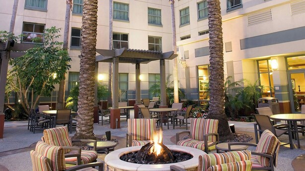 A hotel courtyard with outdoor seating, palm trees, and a fire pit. - Residence Inn by Marriott Irvine John Wayne Airport (Irvine)