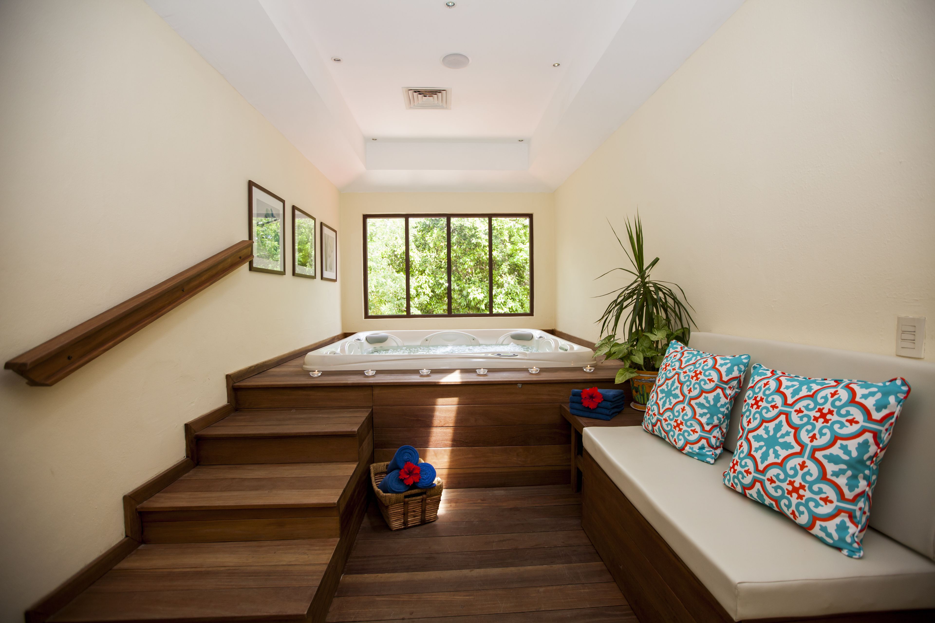 Uma área de spa com escada de madeira, hidromassagem e sofá com almofadas estampadas.