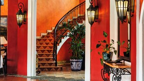 A red-walled hallway with a wooden ceiling, a staircase, and potted plants. - Occidental Cozumel - All Inclusive (Cozumel)
