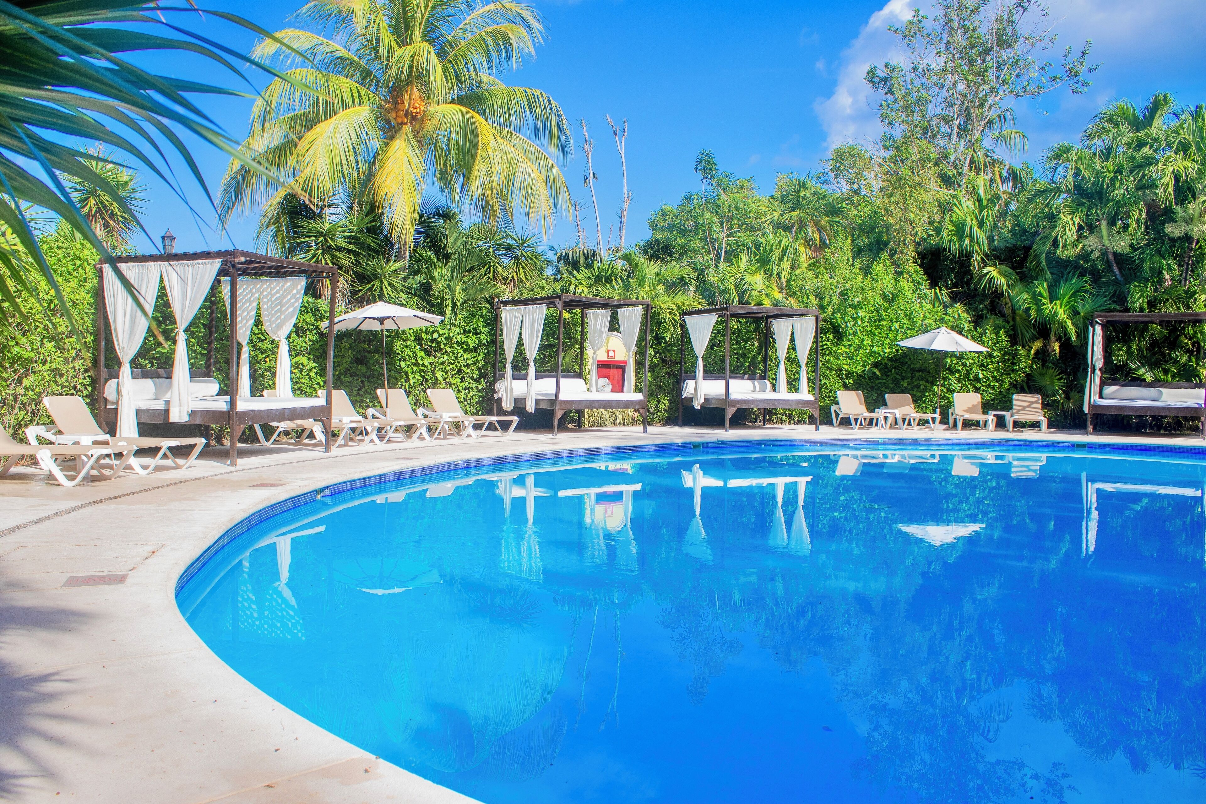 Ein klares, blaues Schwimmbecken mit Liegestühlen und Cabanas.