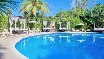 A clear blue swimming pool with lounge chairs and cabanas.