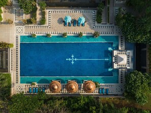 Vista aérea de una piscina con un diseño geométrico de azulejos, tumbonas y elementos decorativos.