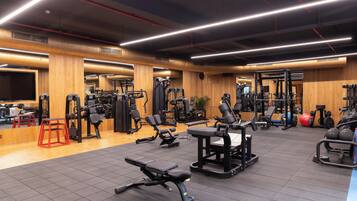 Een sportschool met diverse fitnessapparaten, houten wanden en een betegelde vloer.