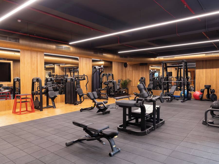 Een sportschool met diverse fitnessapparaten, houten wanden en een betegelde vloer.