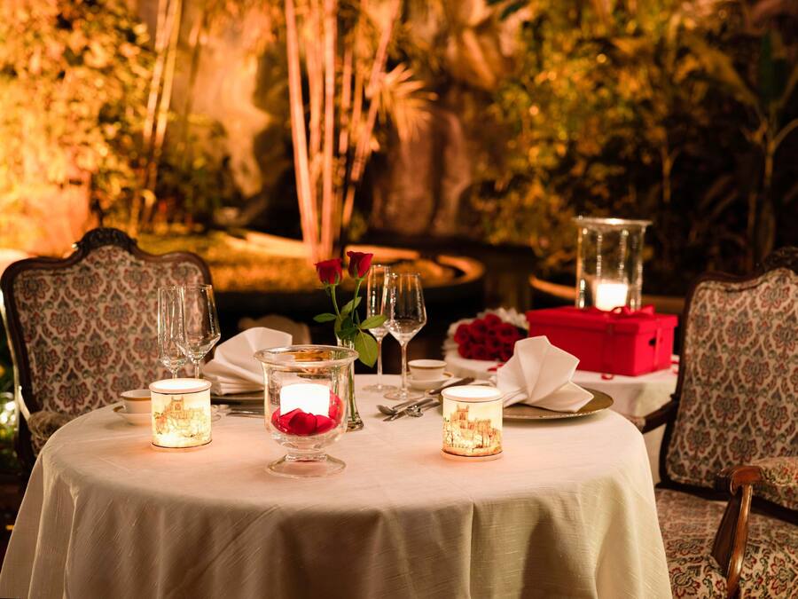 A table set for dining with candles, glasses, and a vase of flowers.