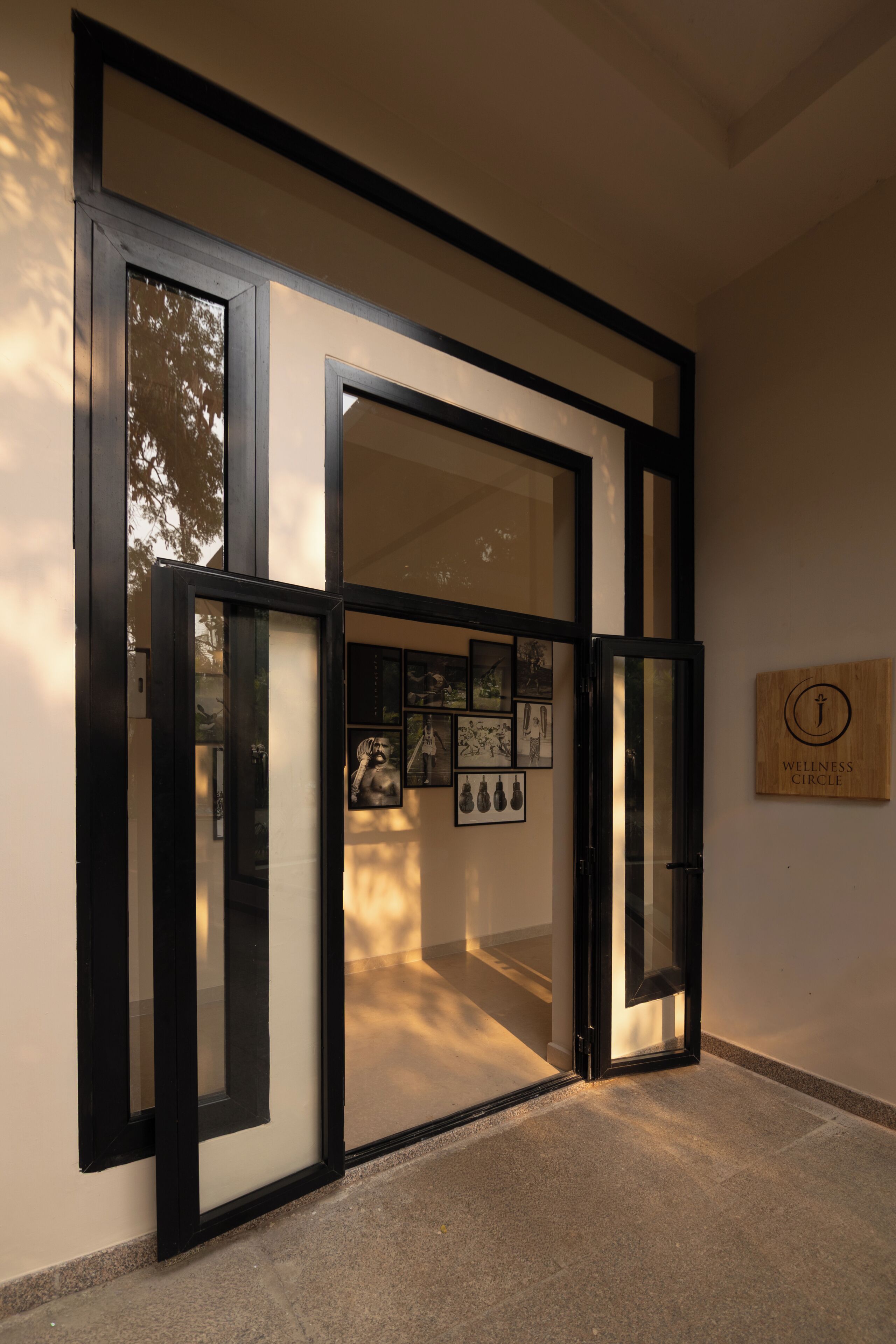 A modern interior with a glass door, framed artwork, and a sign reading 'Wellness Circle'.