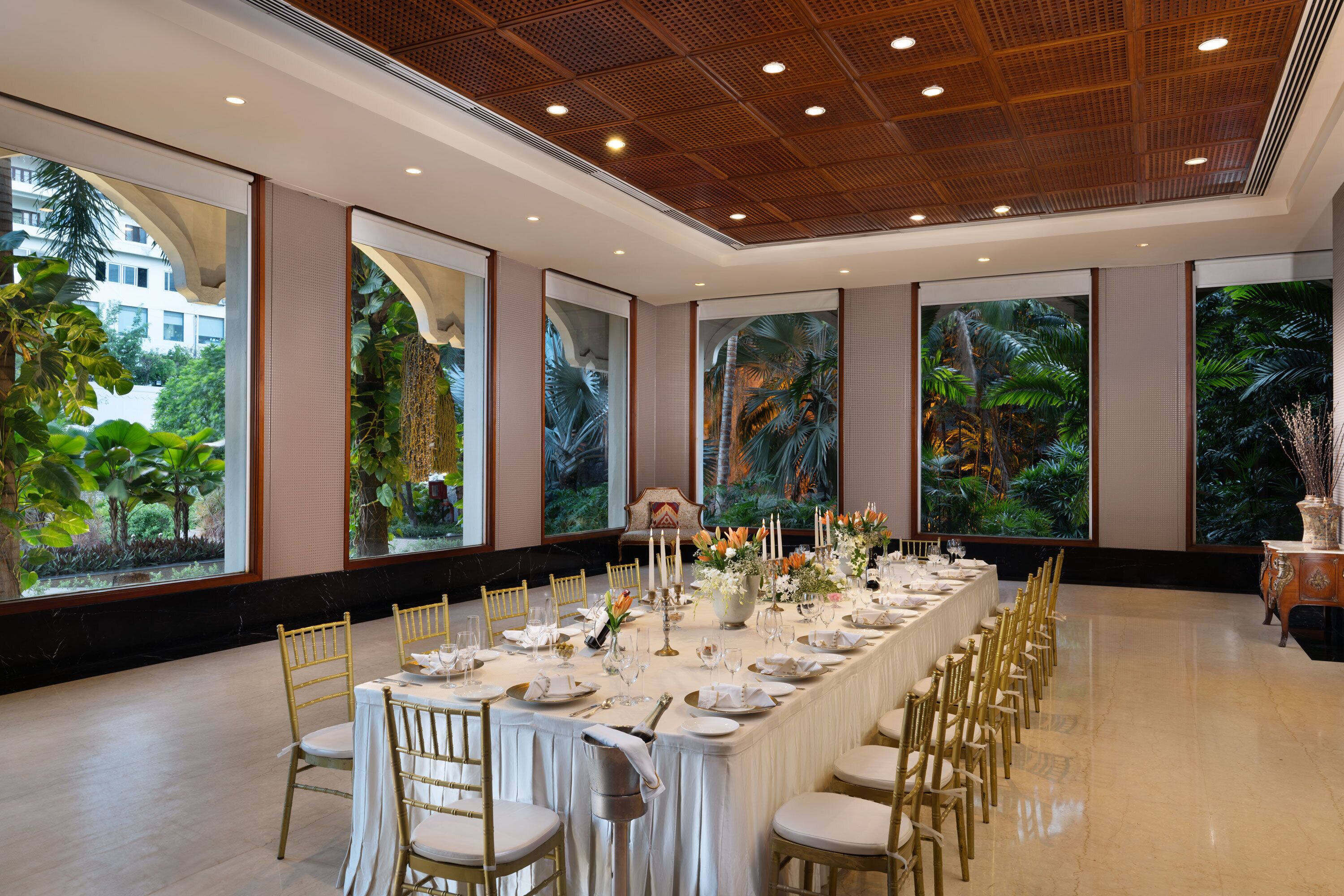 Una larga mesa de banquete dispuesta para un evento formal, con sillas, velas y arreglos florales.
