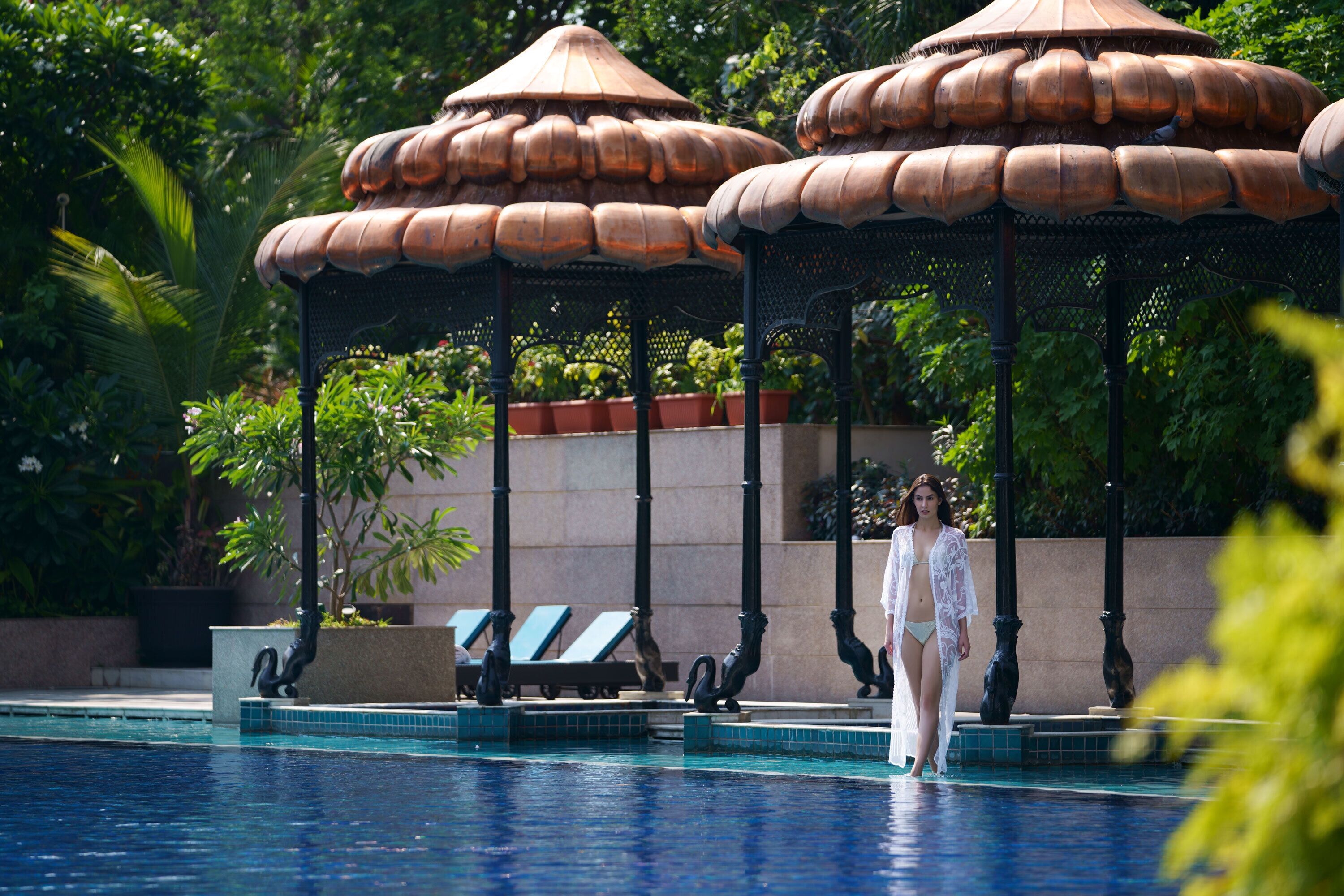 A pool area with lounge chairs and a gazebo structure.
