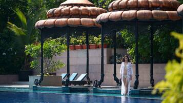 A pool area with lounge chairs and a gazebo structure.