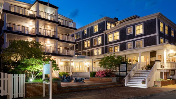 A multi-story hotel with a grand entrance, a flagpole, and a well-lit facade. - Vineyard Square Hotel & Suites (Edgartown)