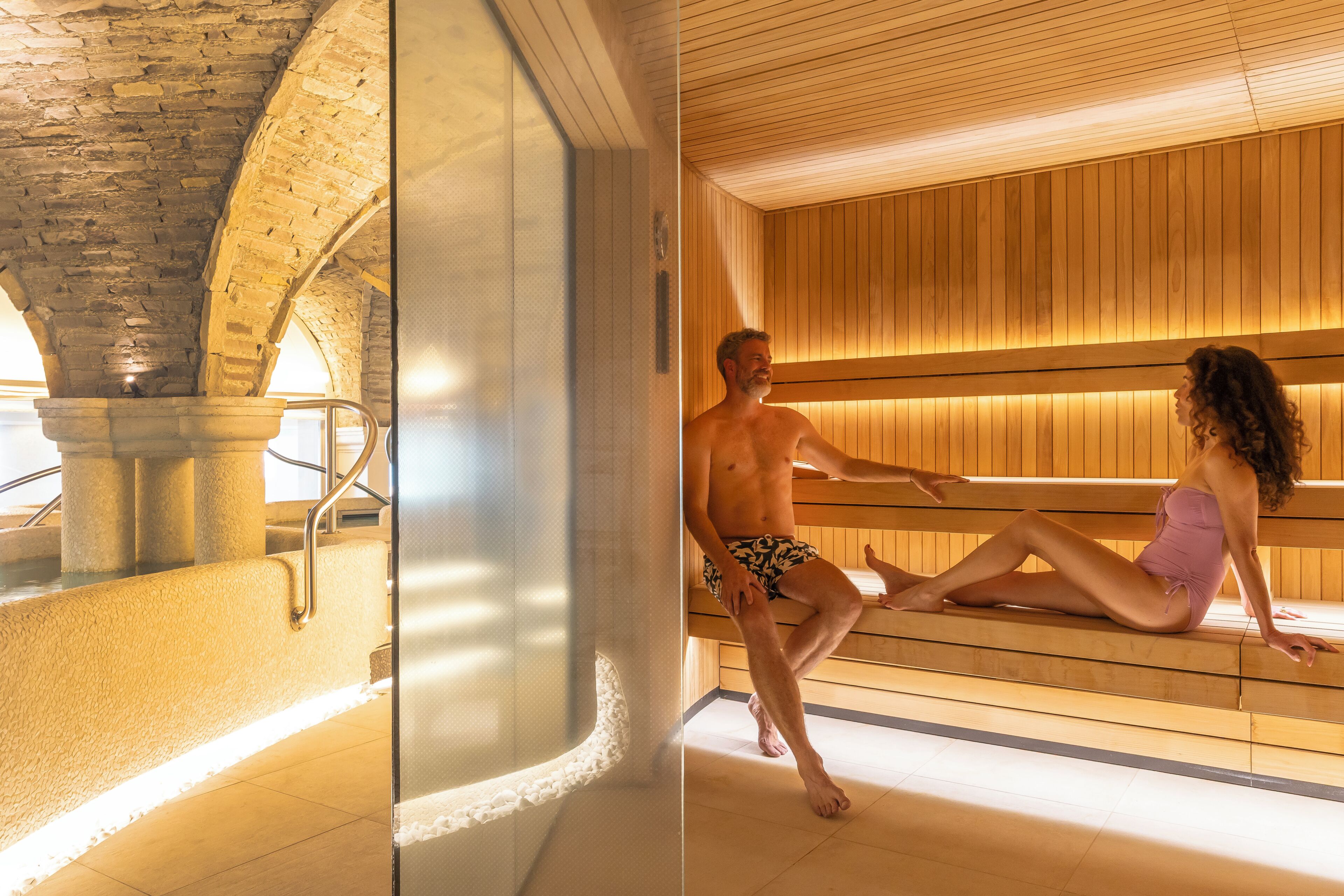 Una sauna con architettura in pietra e panche in legno.