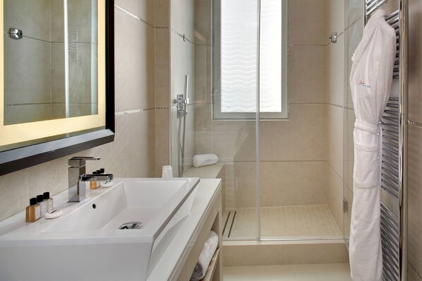 A modern bathroom with a large sink, a glass shower enclosure, and a towel rack.