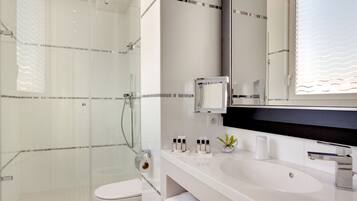 A modern bathroom with a glass shower enclosure, a white sink, and a large mirror.