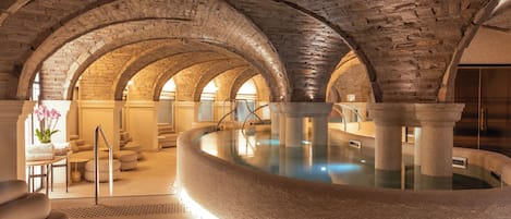 A spa area with a stone pool, arched ceilings, and seating.
