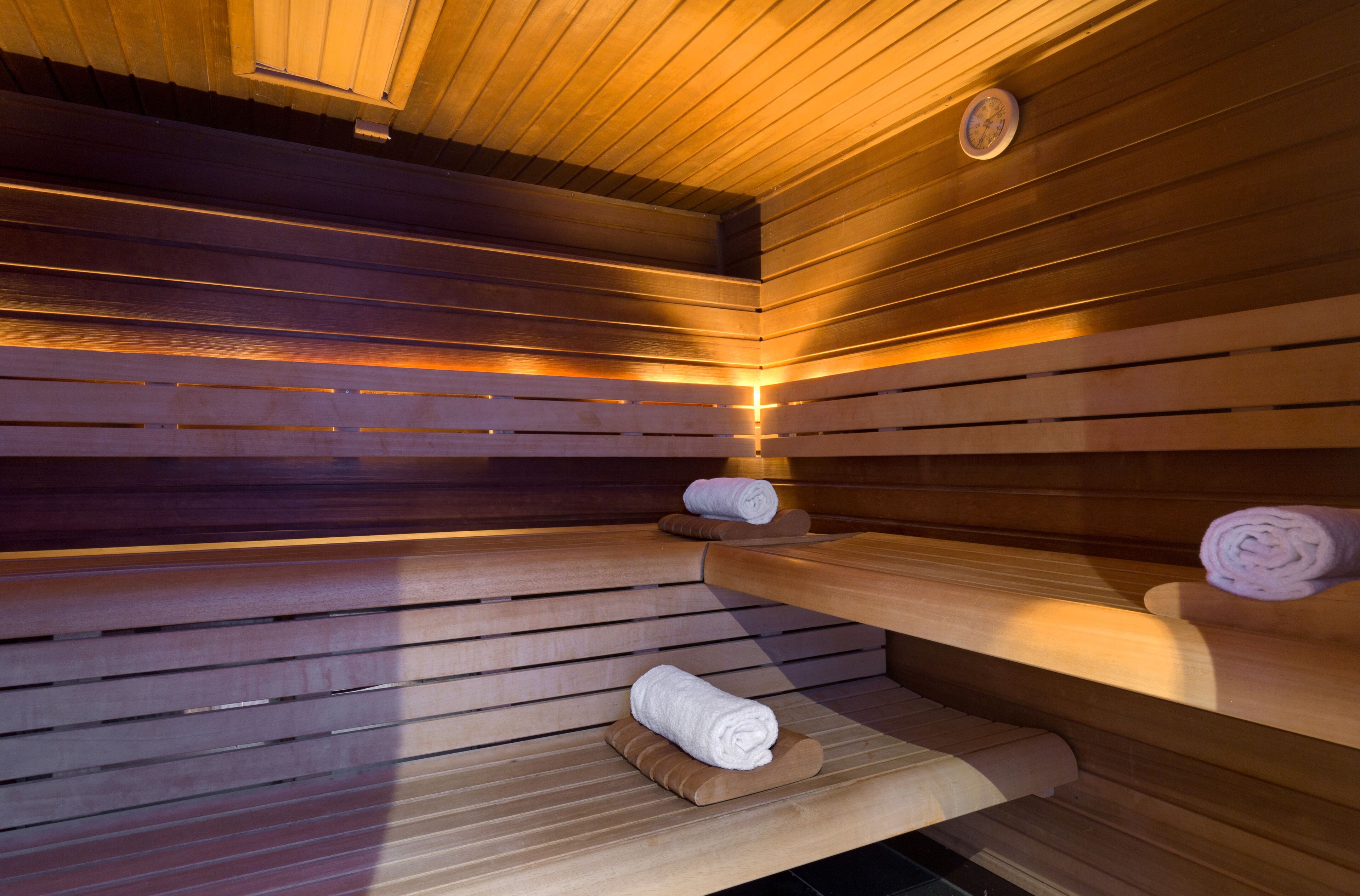 Un sauna avec des bancs en bois et des serviettes disposées sur ces bancs.