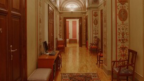 A hallway with wooden floors, a patterned rug, and ornate ceiling decorations. - Relais Pierret (Rome)