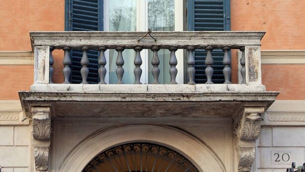 A building facade with a sign reading "E. PIERRET" above a window with blue shutters. - Relais Pierret (Rome)