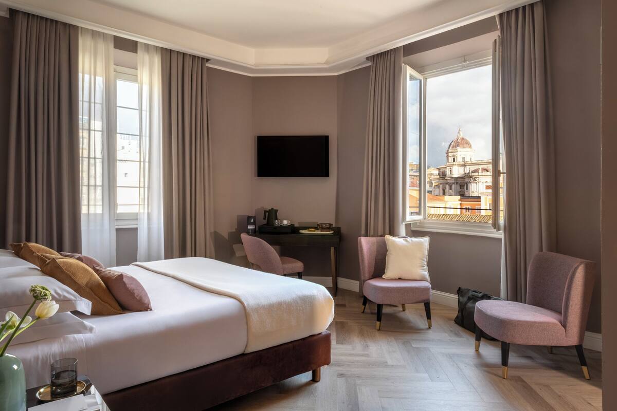 A hotel room with a bed, a desk, a chair, and a TV.
