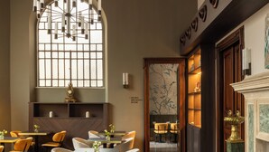 A restaurant with a modern interior, featuring a chandelier, tables with chairs, and a decorative wall with a clock. - Hotel Viminale (Rome)
