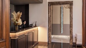 A modern hotel lobby with a polished marble floor, a reception desk with a vase of flowers, and a large mirror with a decorative frame. - Hotel Viminale (Rome)