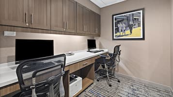 A modern office space with a long desk, two chairs, a printer, and a framed picture on the wall.