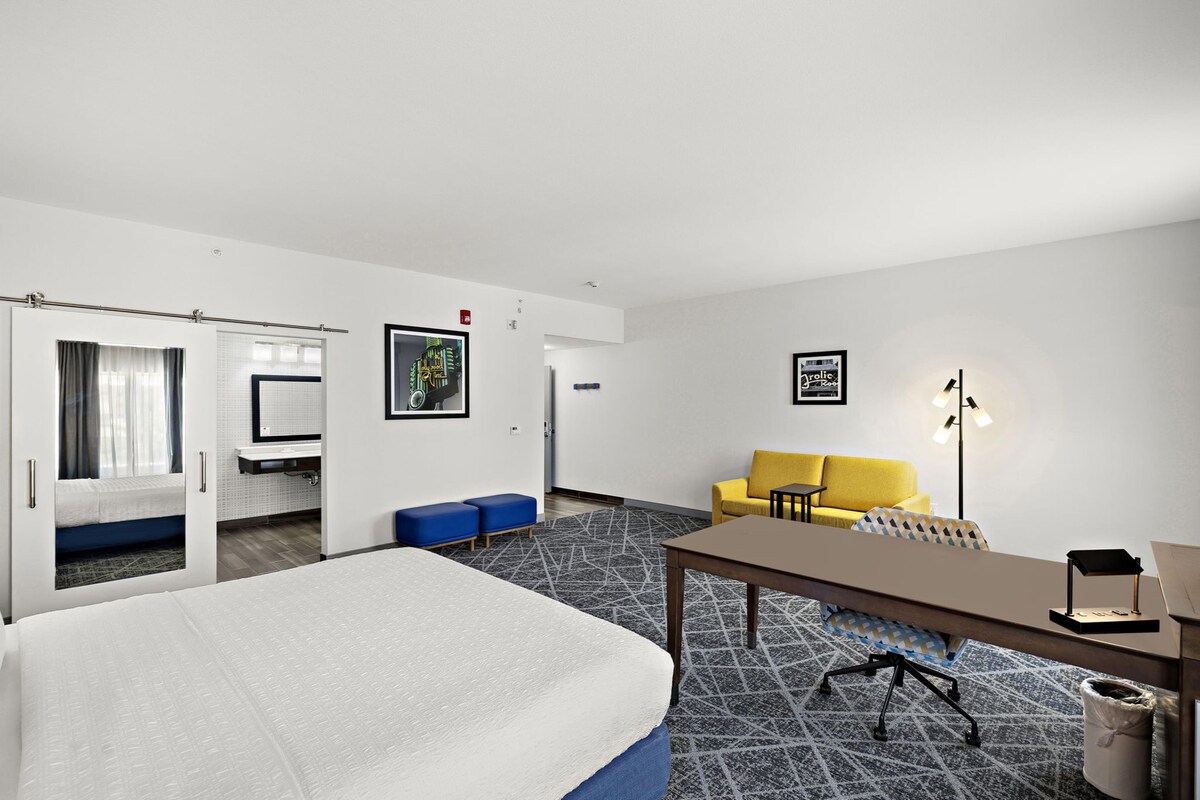 A hotel room with a bed, a desk, a sofa, and a small table.