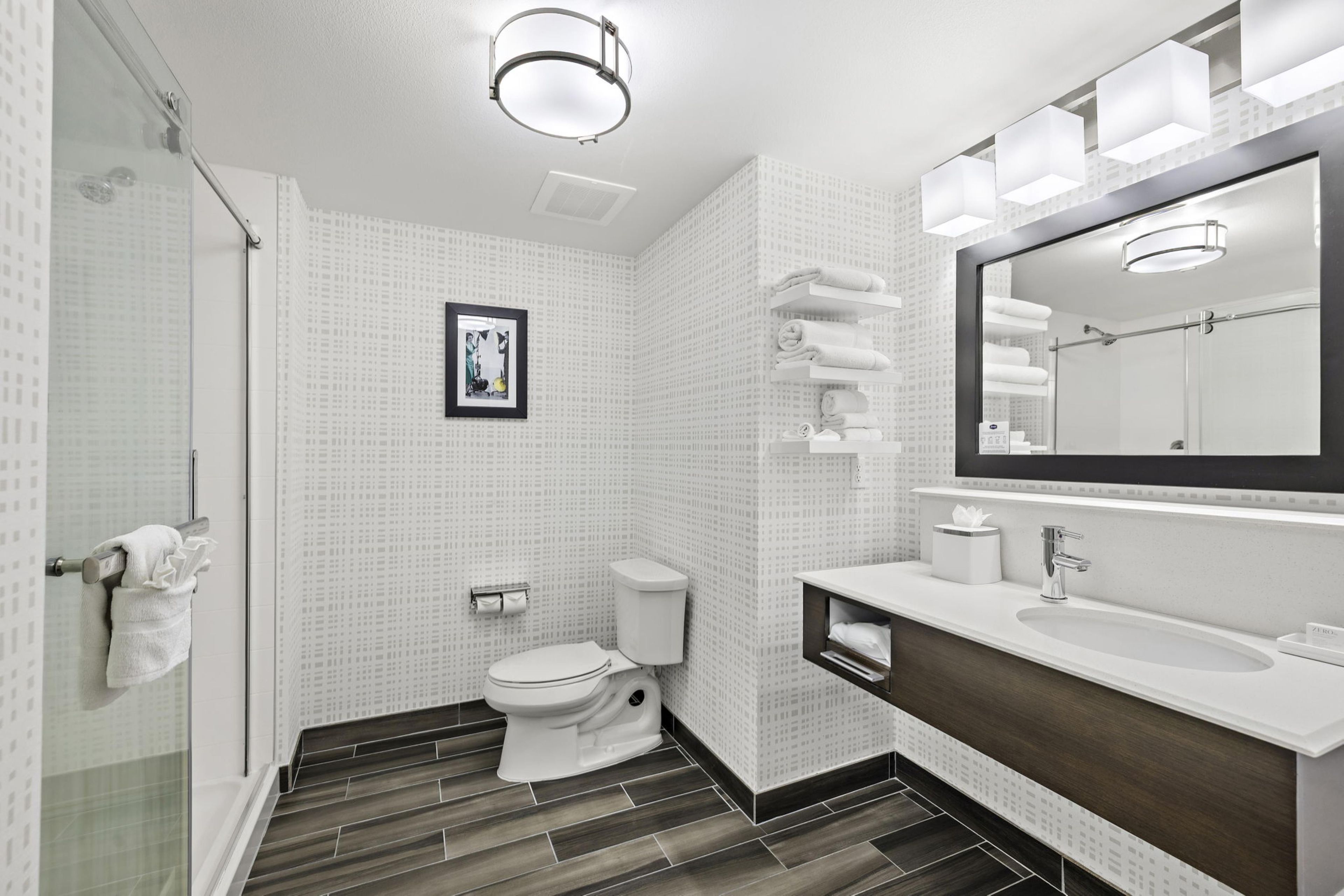 A modern bathroom with a shower, toilet, and vanity.