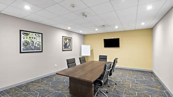 A conference room with a long table, chairs, a whiteboard, and two framed pictures on the wall.