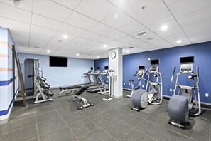 A gym with various exercise equipment, a clock, and a blue wall. - Hampton Inn & Suites Los Angeles/Hollywood (Los Angeles)