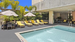 A rooftop pool area with sun loungers and umbrellas, surrounded by greenery. - Hampton Inn & Suites Los Angeles/Hollywood (Los Angeles)