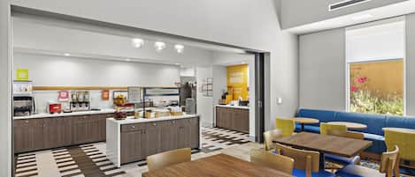 A modern breakfast area with a kitchen, seating, and a view of the outdoors.