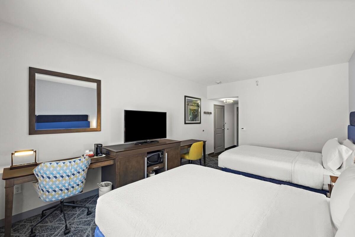 A hotel room with a bed, a desk, a chair, a television, and a bathroom door.