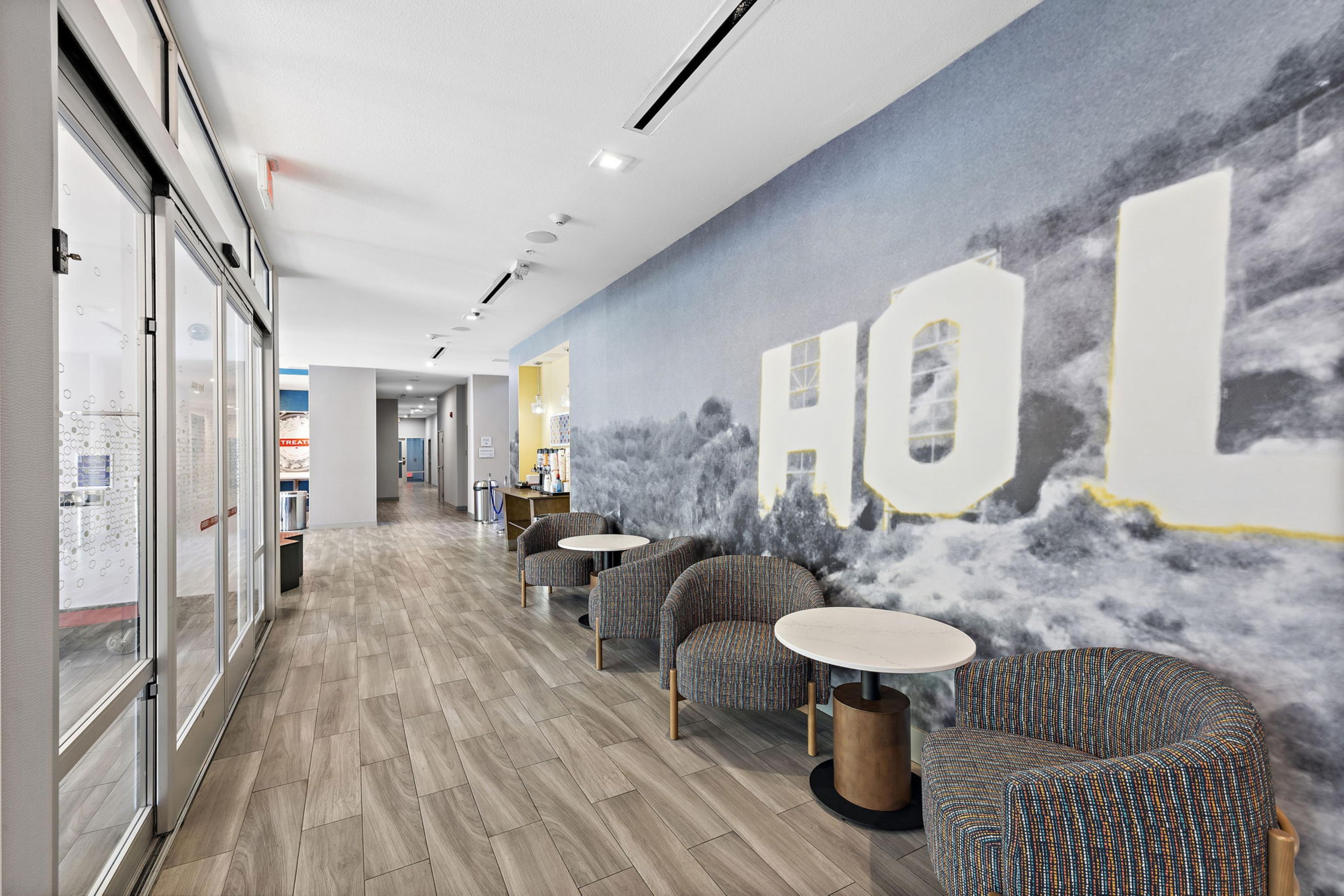 A modern interior with a long corridor, patterned chairs, and a wall mural.