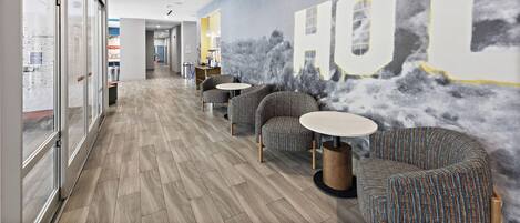 A modern interior with a long corridor, patterned chairs, and a wall mural.