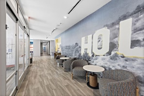 A modern interior with a long corridor, patterned chairs, and a wall mural. - Hampton Inn & Suites Los Angeles/Hollywood (Los Angeles)