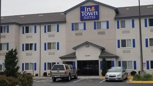 A hotel with a sign reading "In Town Suites" and the number 14090. There are cars parked in front and a small landscaped area with shrubs.