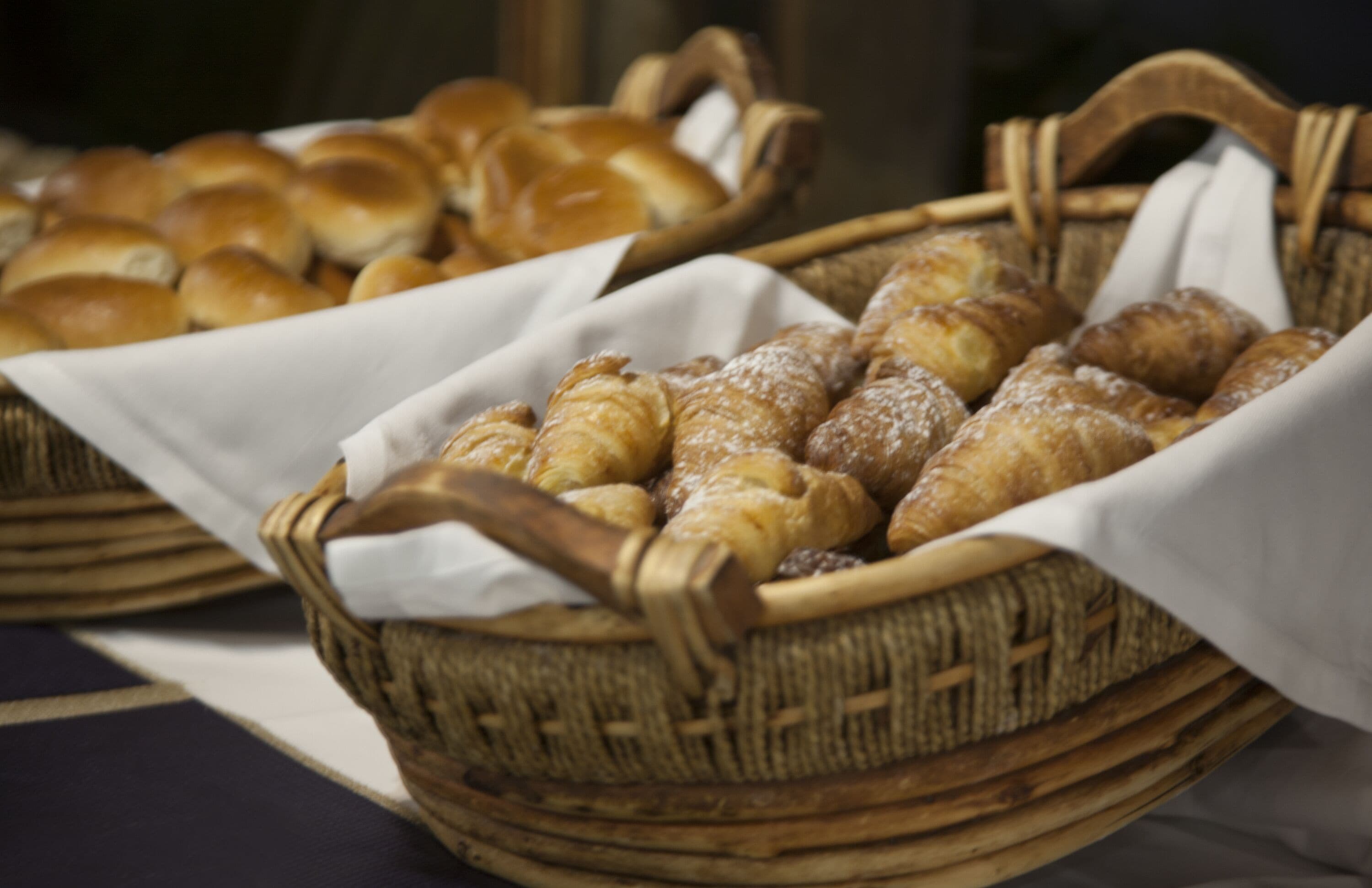 Una cesta con una variedad de productos horneados, como panecillos y pasteles, probablemente a la venta.