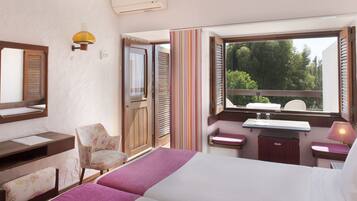 Une chambre d’hôtel comprenant un lit, un bureau, une chaise, une fenêtre donnant sur des arbres, ainsi qu’une salle de bain avec un lavabo et un miroir.