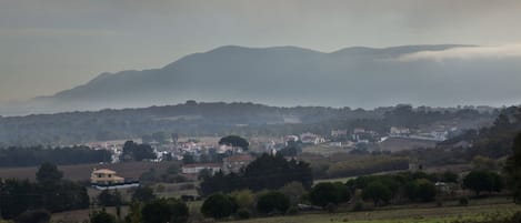 A rural landscape with a village, houses, and mountains in the background.