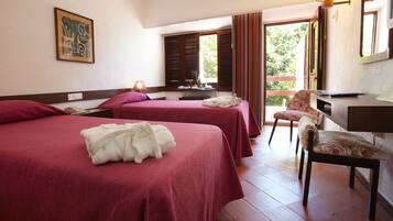 A hotel room with two beds, a desk, a chair, and a window with blinds.