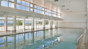 A large indoor swimming pool with clear views of the ocean through large windows. - Hotel Do Mar (Sesimbra)
