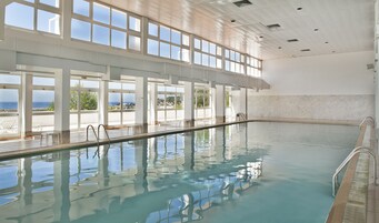 Una piscina al aire libre, sombrillas, sillones reclinables de piscina