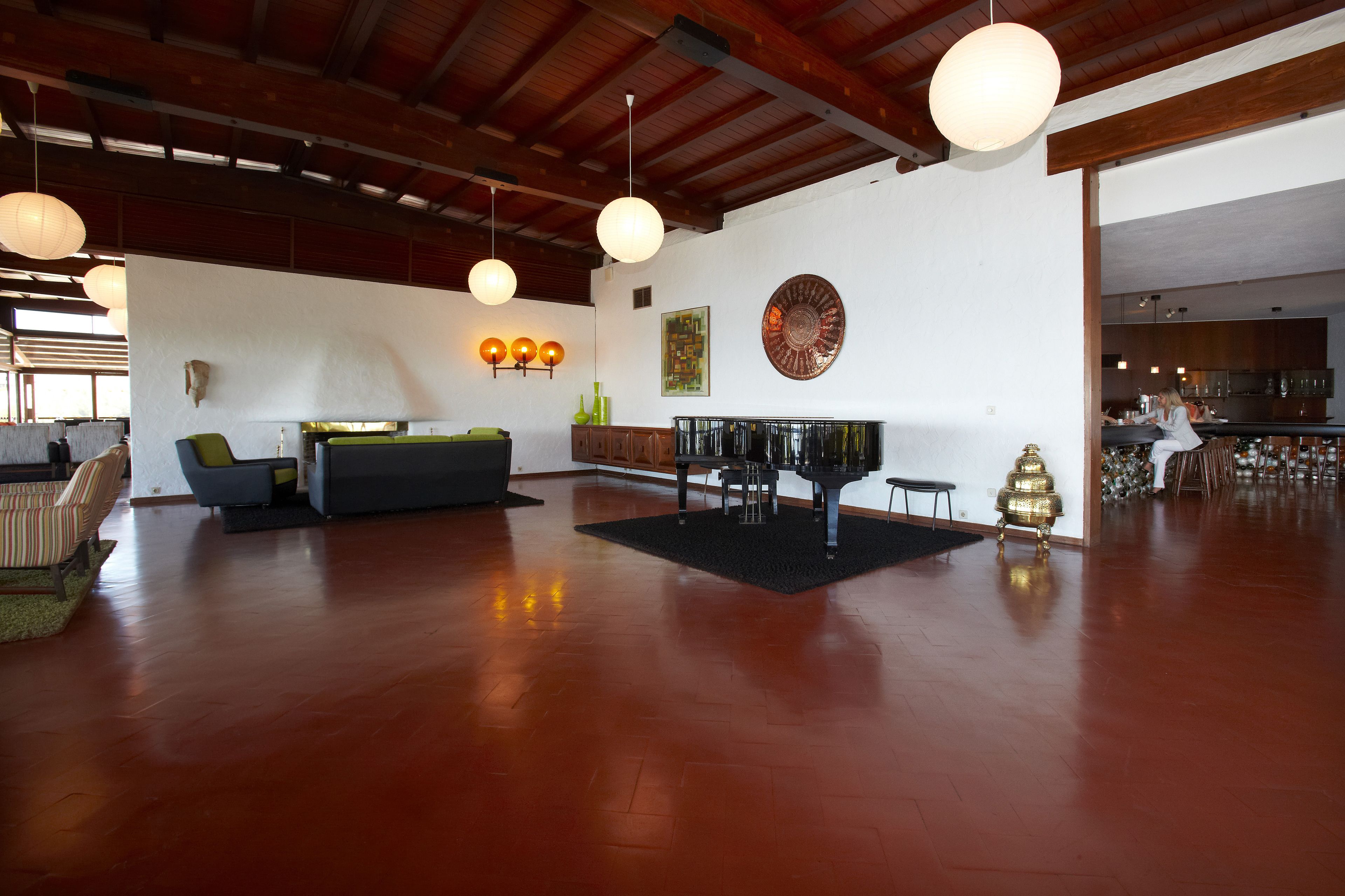 A spacious living area with a wooden floor, a sofa, a coffee table, and pendant lighting.