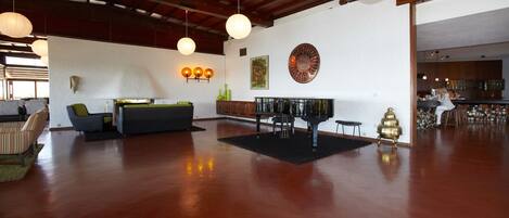 A spacious living area with a wooden floor, a sofa, a coffee table, and pendant lighting.