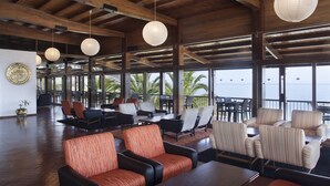 A spacious indoor area with multiple seating arrangements, large windows, and a view of the sea. - Hotel Do Mar (Sesimbra)