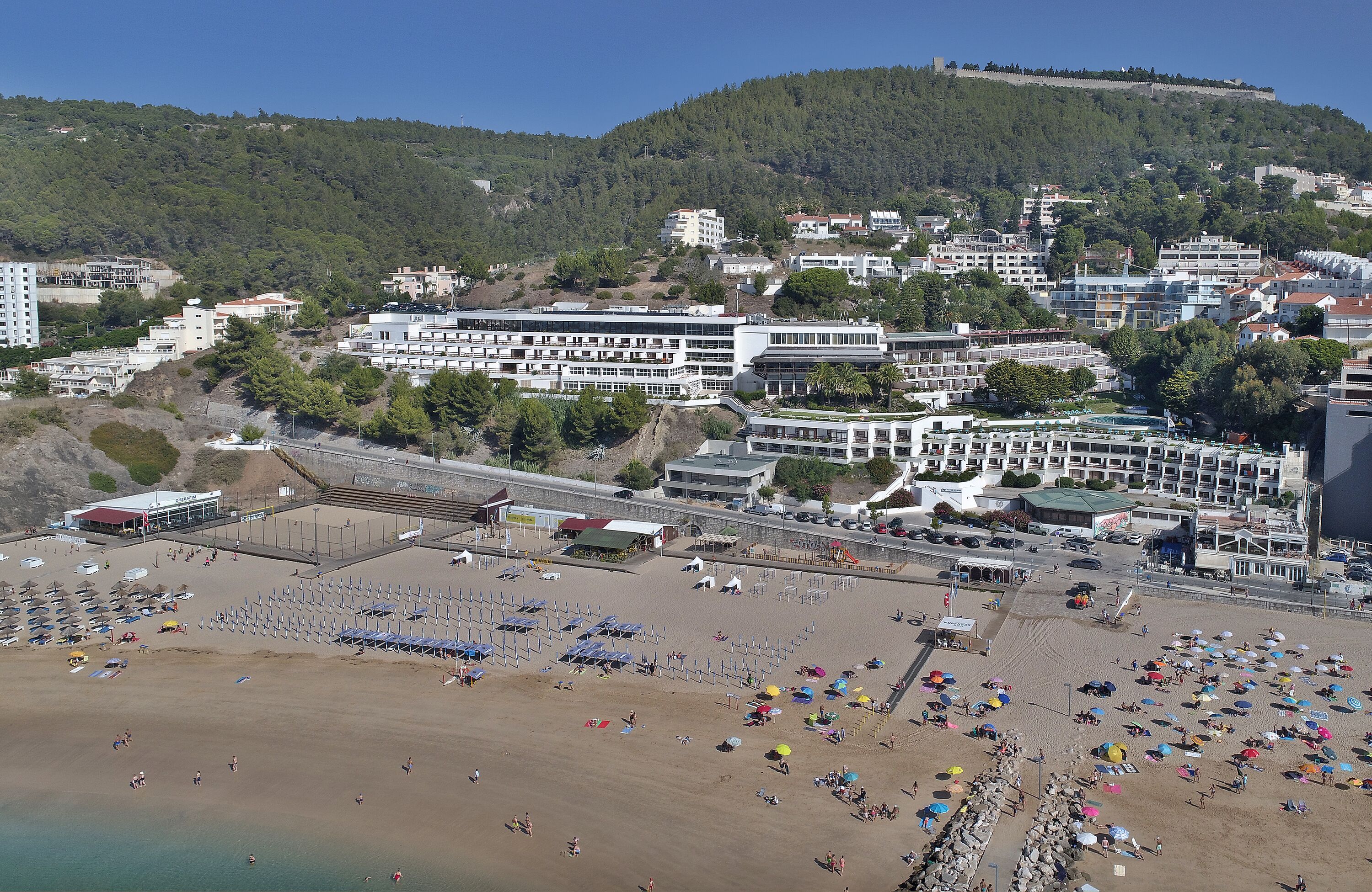 Eine Küstenstadt mit Strand, Gebäuden und einer Hügelkette im Hintergrund.