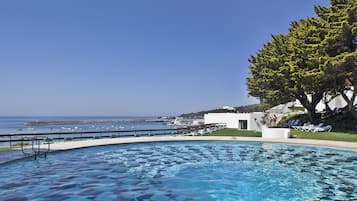 Una piscina al aire libre, sombrillas, sillones reclinables de piscina