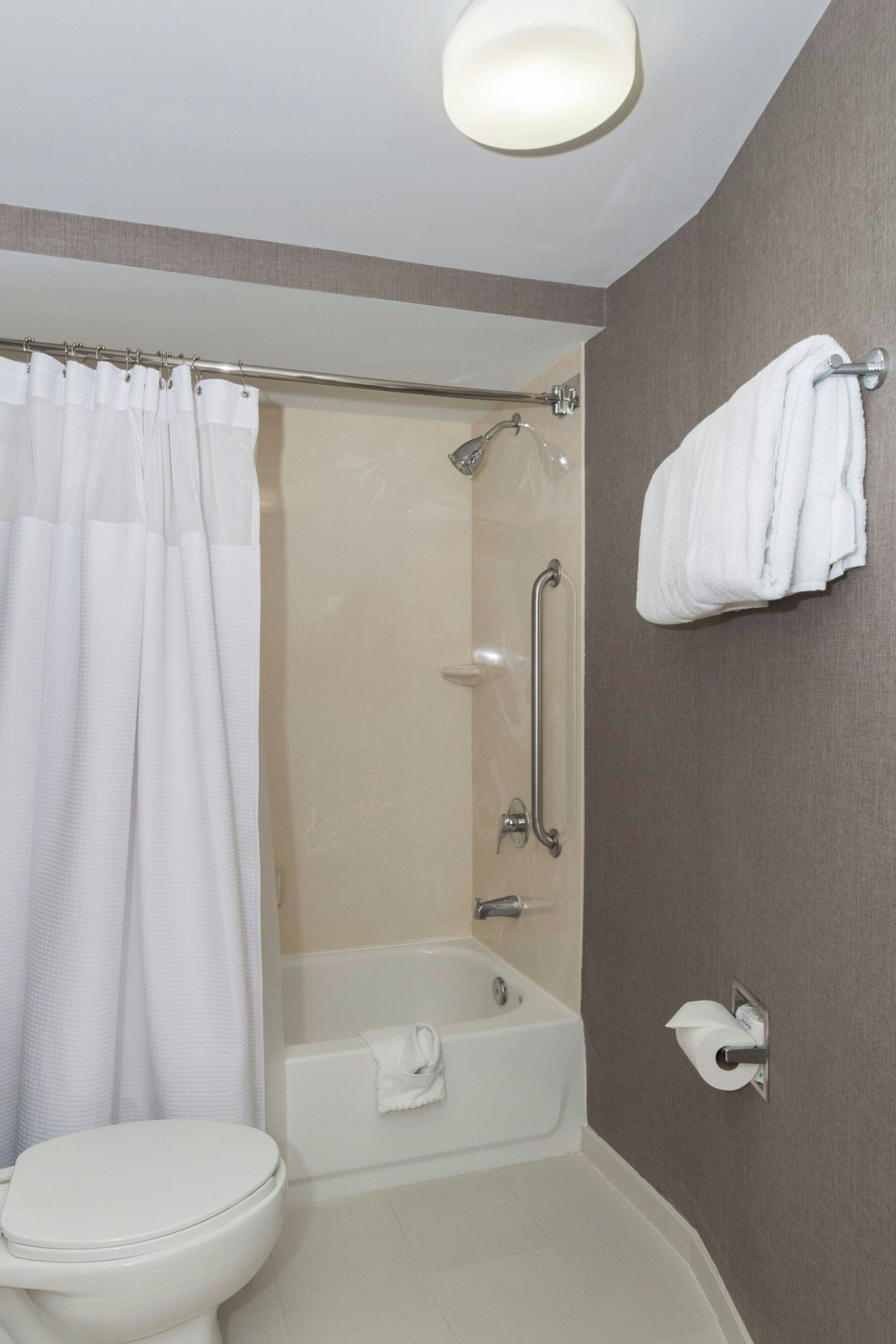 A bathroom with a toilet, a bathtub, a shower, and a towel rack.