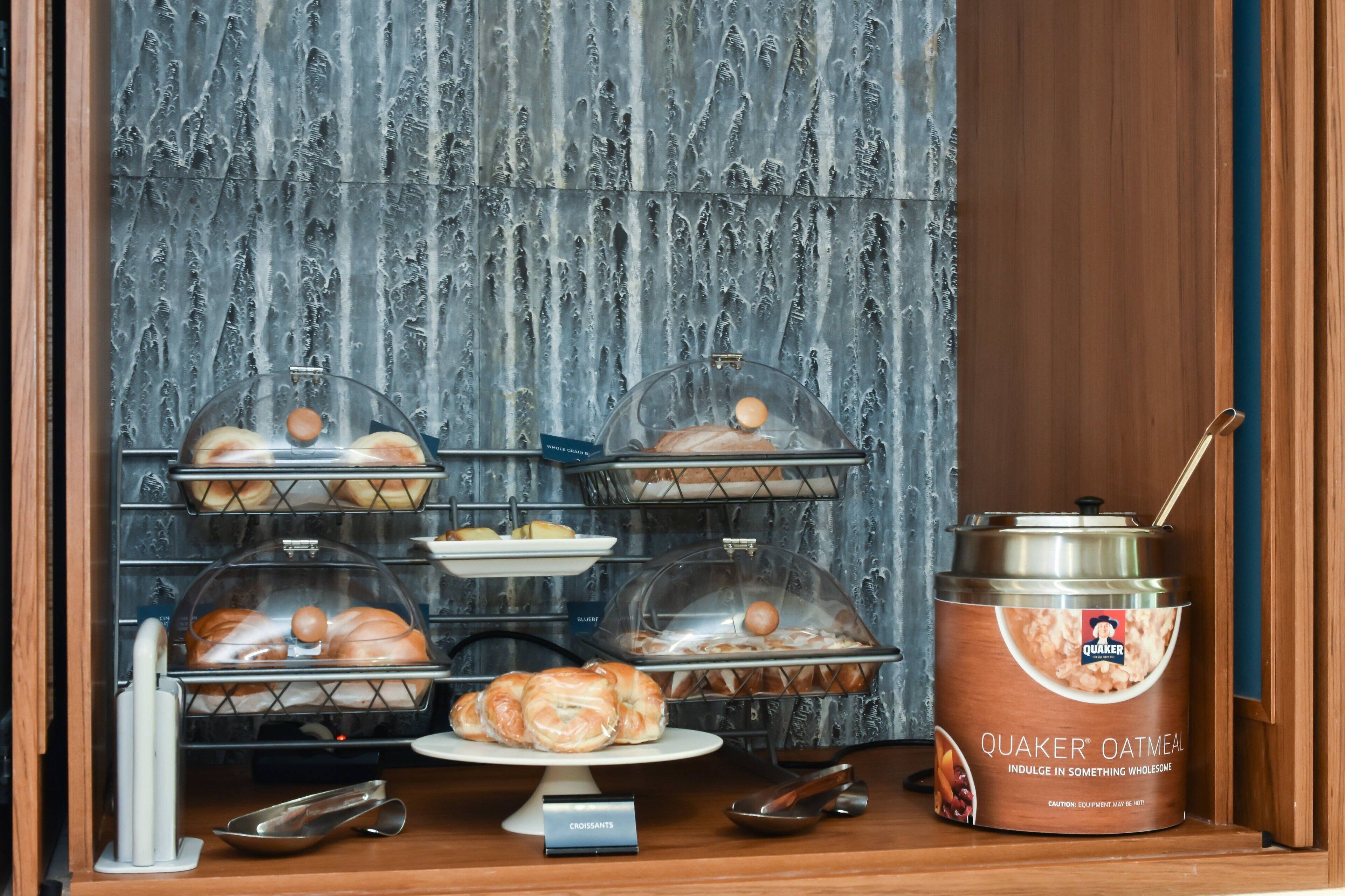 Exposição de café da manhã com croissants, muffins e aveia Quaker.